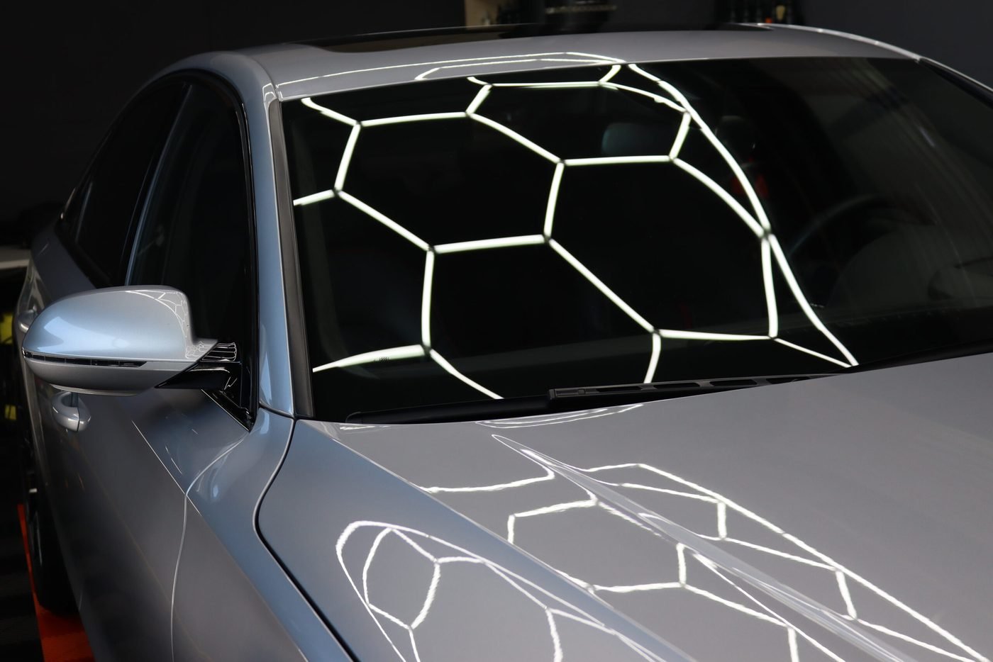 Silberne Limousine mit der Spiegelung der Deckenleuchten auf Scheibe und Motorhaube